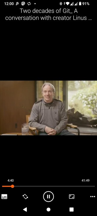 The screencap showcases a VLC video player interface on an Android with a video titled "Two decades of Git: A conversation with creator Linus..." The video is currently at 4:40 out of a total duration of 41:49. The video features a man Linus Torvalds sitting in a chair, wearing a gray long-sleeve shirt with a small logo on the left side, and dark pants. He is seated in front of a large window with a view of greenery outside. There are two glasses of water on a small table to his left. The background includes a wooden wall and a large window, suggesting an indoor setting with natural light. The video player interface includes standard controls such as play, pause, and volume adjustment, along with a progress bar indicating the current playback position.

 Ovis2-8B

🌱 Energy used: 0.187 Wh