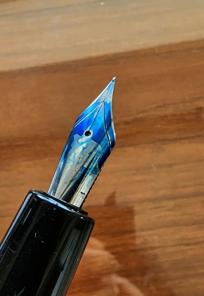 Close-up photo of a nib covered in a brilliant blue ink.