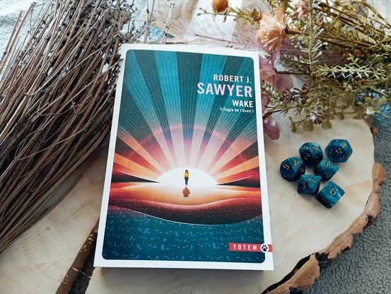 Une photo du livre Trilogie de l'éveil, tome 1 : Wake de Robert J. Sawyer entouré d'objets de décoration.