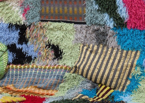 a detail of a textile sculpture showing numerous textures and colors with many fiber ends
