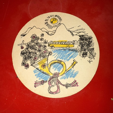 Ein runder Bierdeckel. Das darauf abgebildete Motiv ist eine Zeichnung. Sie zeigt ein gelbes Postauto. Dahinter sind Konturen von Bergen zu erkennen, sowie die gelb strahlende Sonne darüber. Im Vordergrund auf der unteren Hälfte der Zeichnung ist ein grosses gelbes Horn zu sehen, auf dem ein Blümchen gezeichnet ist. Am Griff des Horns schlängelt sich ein Seil zur Dekoration. Aus dem Trichter des Horns kommen Blumenblüten. Auf der rechten Seite ist noch ein kleiner Rest eines Zeiges eines Nadelbaumes zu sehen.