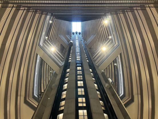 Three elevators descend from the skylight to ground level. The lines are balconies that form angles around the shaft.