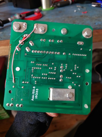 The back of the repaired control box PCB, showing a short higher gauge bodge wire for the smaller +12V line and a longer, smaller gauge wire between the larger +12V line and the LM342.
