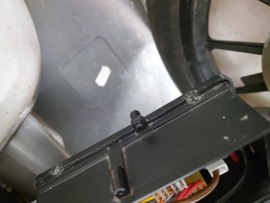 A picture of the black plastic control box case with a small tab protruding from the side with a 3mm black screw going through it with 2 nuts on the other end.
