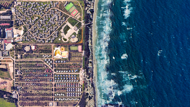 a satellite picture of a seaside resort complex and the sea. th picturee is split in two with the blue sea on the right and the resort + camping on the left