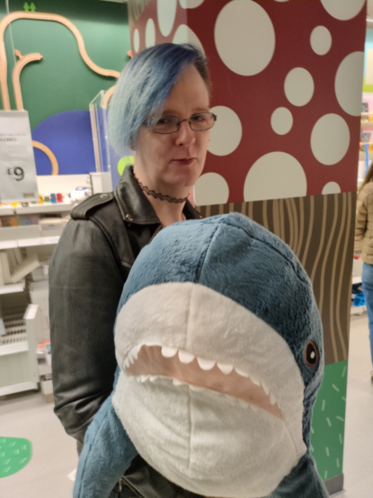 rayne holds a full size blahaj in the showroom area of Ikea Oxford Circus