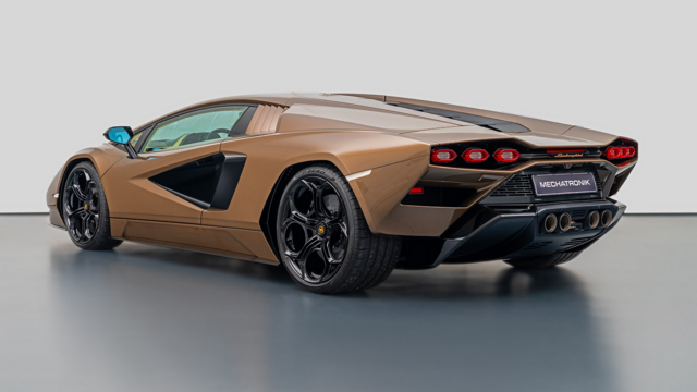 a photo of the vehicle, it is dark gold colored, very wedge shaped and aerodynamic, seen from behind in a three quarter view