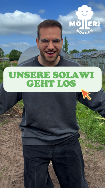 Das Bild zeigt eine Person, die auf einem Feld steht und ein Schild mit der Aufschrift "Unsere Solawi geht los" hält. Die Person trägt ein graues Sweatshirt und Jeans und lächelt in die Kamera. Im Hintergrund sind Gewächshäuser und ein klarer Himmel mit einigen Wolken zu sehen, was darauf hindeutet, dass es sich um eine ländliche oder landwirtschaftliche Umgebung handelt. Das Logo "Möllers Morgen" ist in der oberen linken Ecke des Bildes sichtbar, was darauf hinweist, dass die Person möglicherweise mit diesem Betrieb verbunden ist. Der Text auf dem Schild deutet darauf hin, dass eine neue Initiative oder ein neues Projekt im Zusammenhang mit der Landwirtschaft gestartet wird, möglicherweise eine Solidarische Landwirtschaft (Solawi).