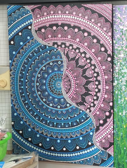 a  mandala  design, cropped  at the  sides, a wavy white line of dots running diagonally, half he mandala is blue, half pink