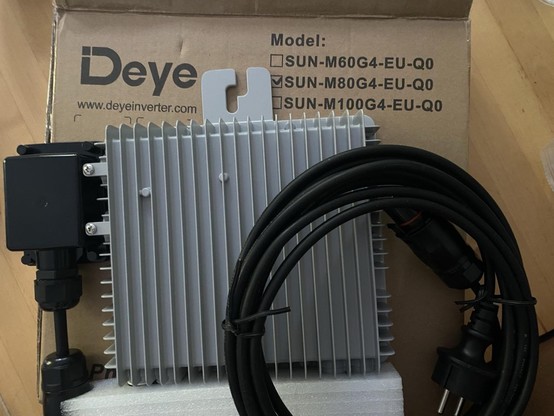 Ein Wechselrichter liegt zusammen mit einem Kabel auf seinem Verpackungs-Karton