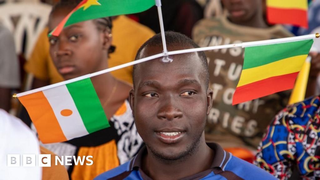 A supporter of the Alliance of Sahel States display the flags of Mali, Niger and Burkina Faso, during a rally in Bamako on 1 February 2024