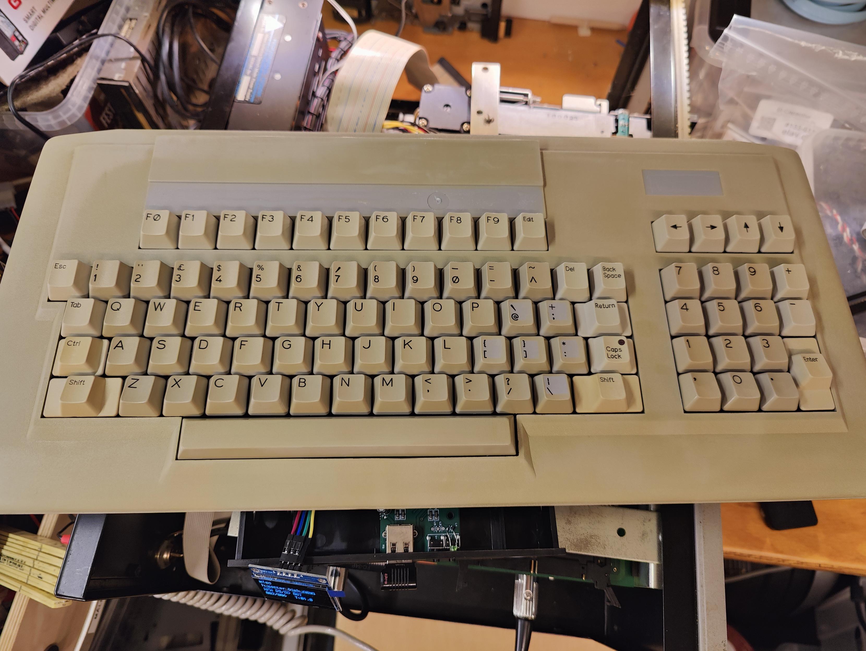 Gemini Microcomputers serial keyboard. Cleaned but with discoloration from aging. Was originally lightht blue, now darker beige. Looks somewhat like a PC keyboard, but without the navigation section. F-keys start with F0. Arrows in a like over the numeric keypad.