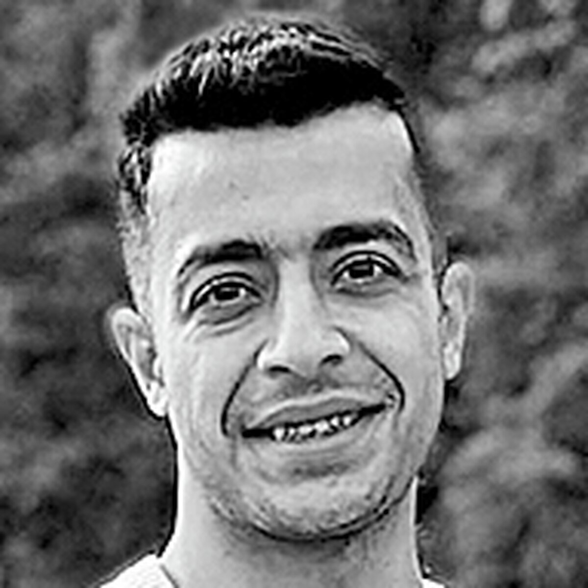 Eine Menschenmenge protestiert. Im Vordergrund sitzt ein Mann, dem Betrachter den Rücken zugewandt, auf den Schultern einer weiteren Person und reckt seine Arme in die Höhe