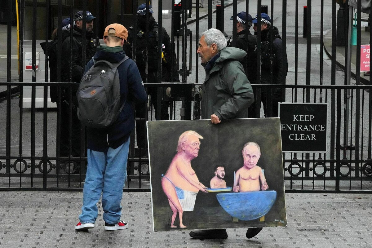 Eine Person geht mit einem Gemälde, das den US-Präsidenten Donald Trump, den ukrainischen Präsidenten Wolodymyr Selenskyj und den russischen Präsidenten Wladimir Putin zeigt vor den Toren der Downing Street 10 in London entlang