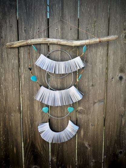 A work of art with a branch at the top and three layers of papers strung such that each strand has 412 lines of a poem. Various beads and hoops decorate the piece. To use it, randomly select a line from each set of strand to make one of over 73million haiku.