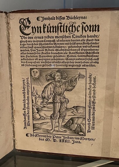 Old book. Picture of man with sun behind him holding his hand up.