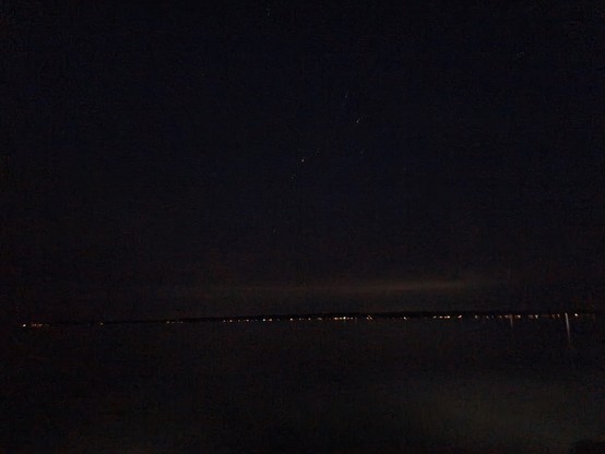 Nighttime phonecam, stars over lit houses on the far shore