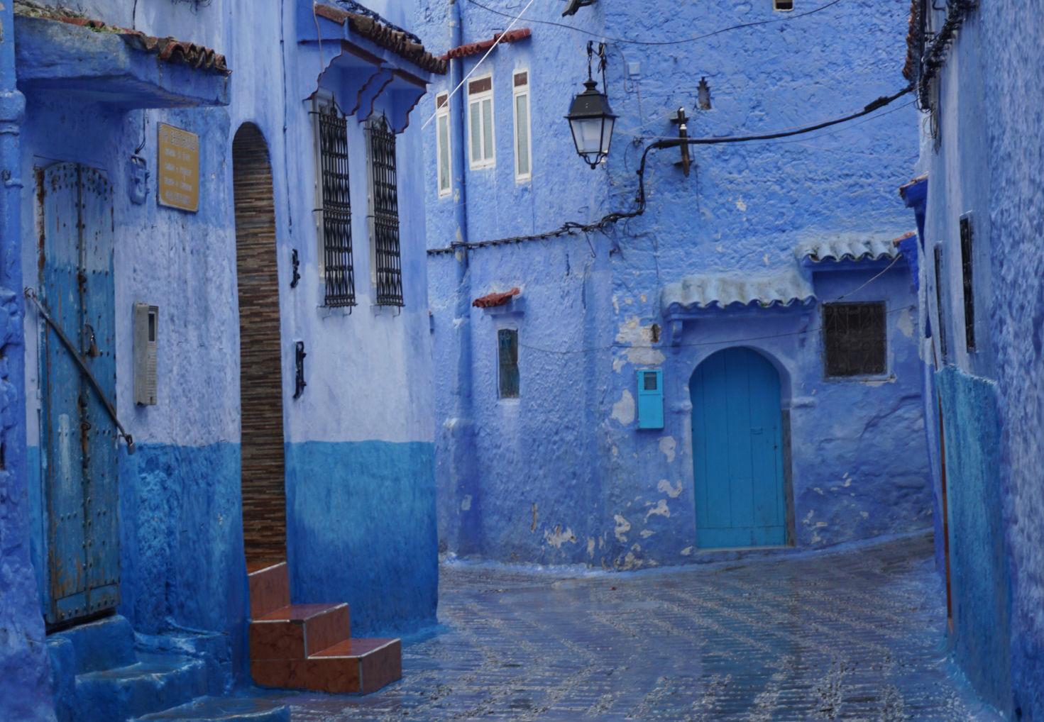 A street scene of houses and buildings on a rainy and overcast day. Everything is a shade of blue except some white window frames, terracotta steps, a black lamp and some other objects. Everything is wet so even the pavement looks blue in places. A street scene of houses and buildings on a rainy and overcast day. Everything is a shade of blue except some white window frames, terracotta steps, a black lamp and some other objects. Everything is wet so even the pavement looks blue in places.