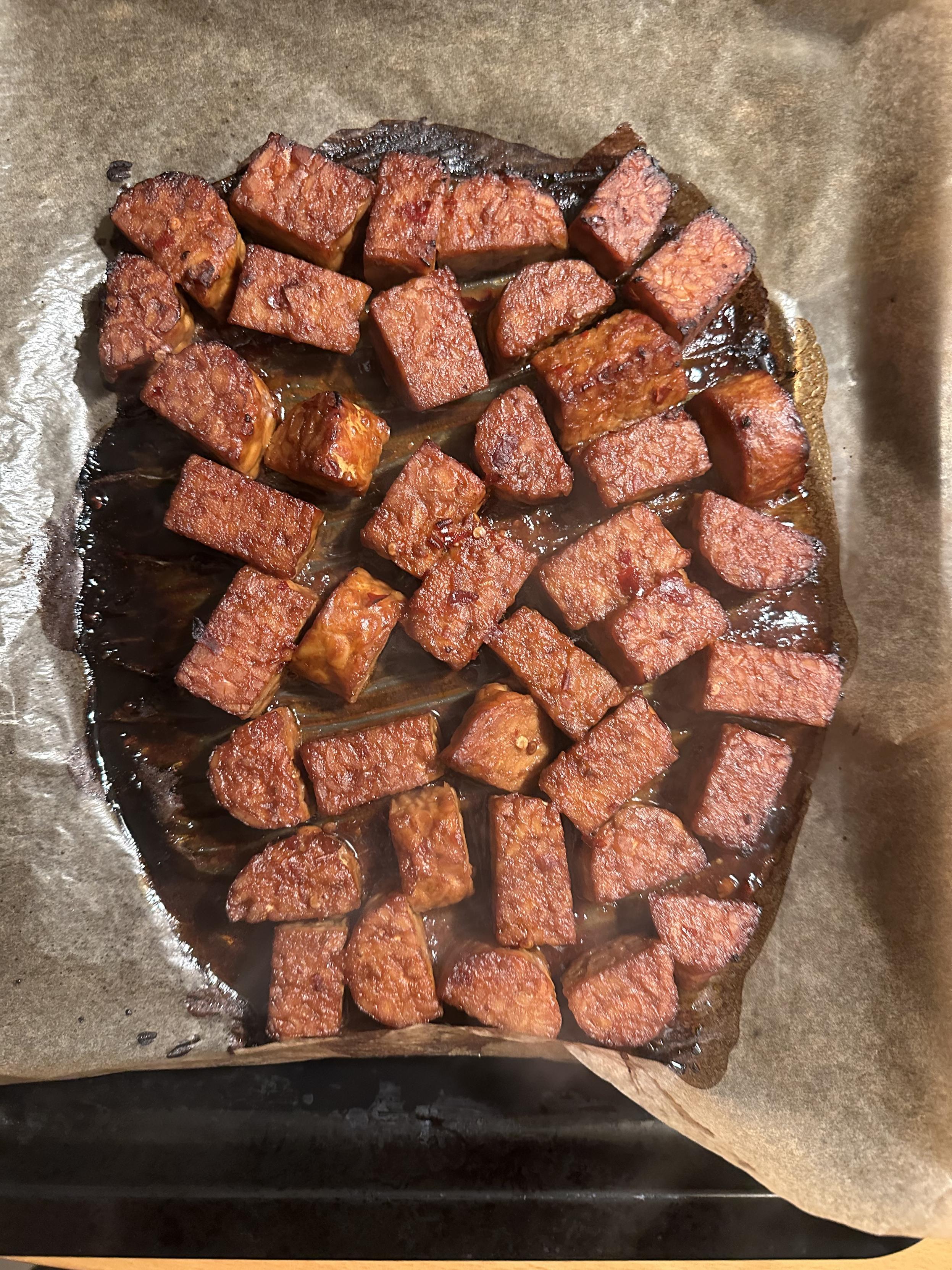 Marinated oven-baked tempeh. The colour is super rich and deep and the edges have started to burn a bit so you know it's crispy.