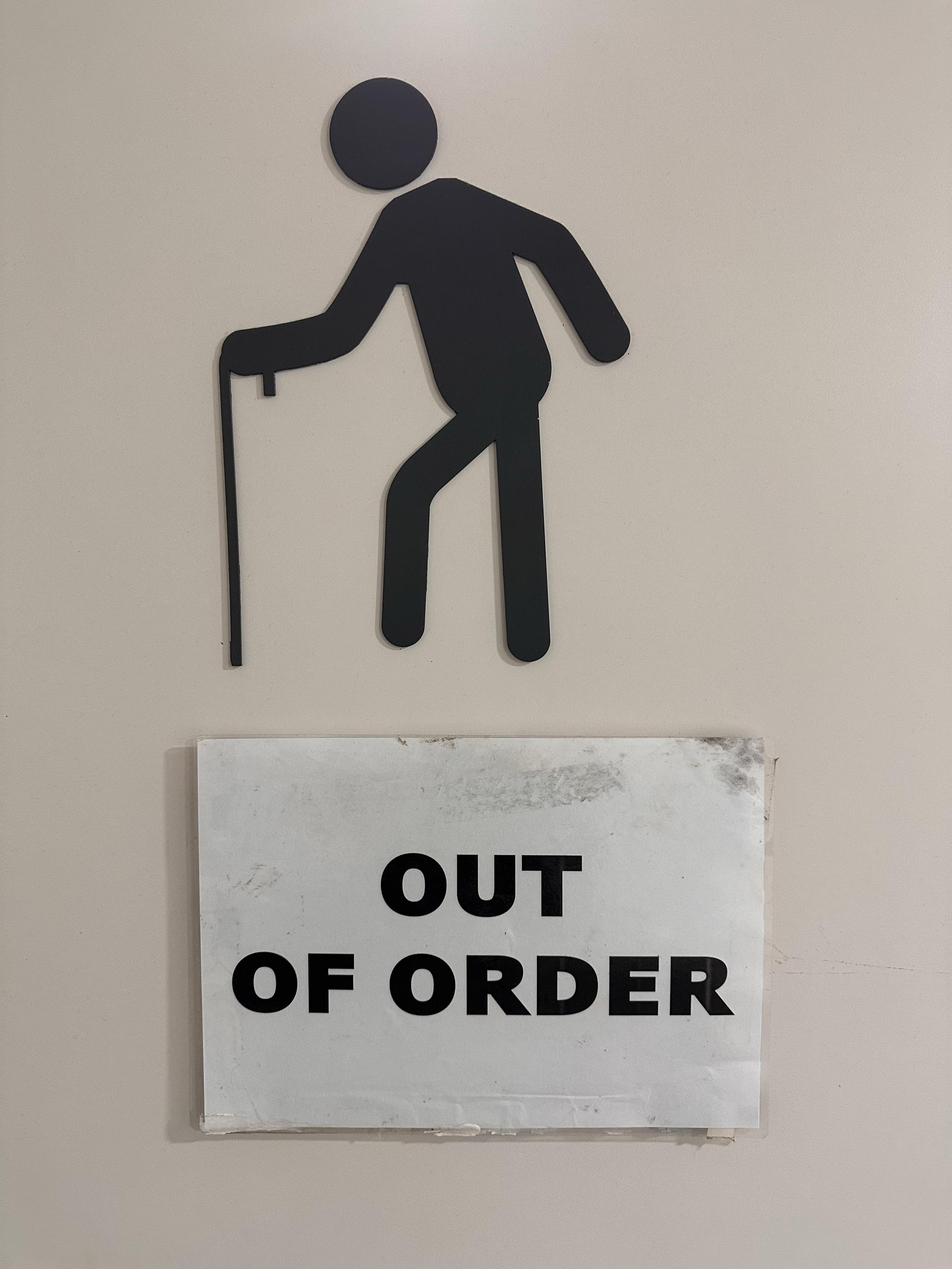 Pictogram of a person with a walking stick above a sign that says “out of order”
