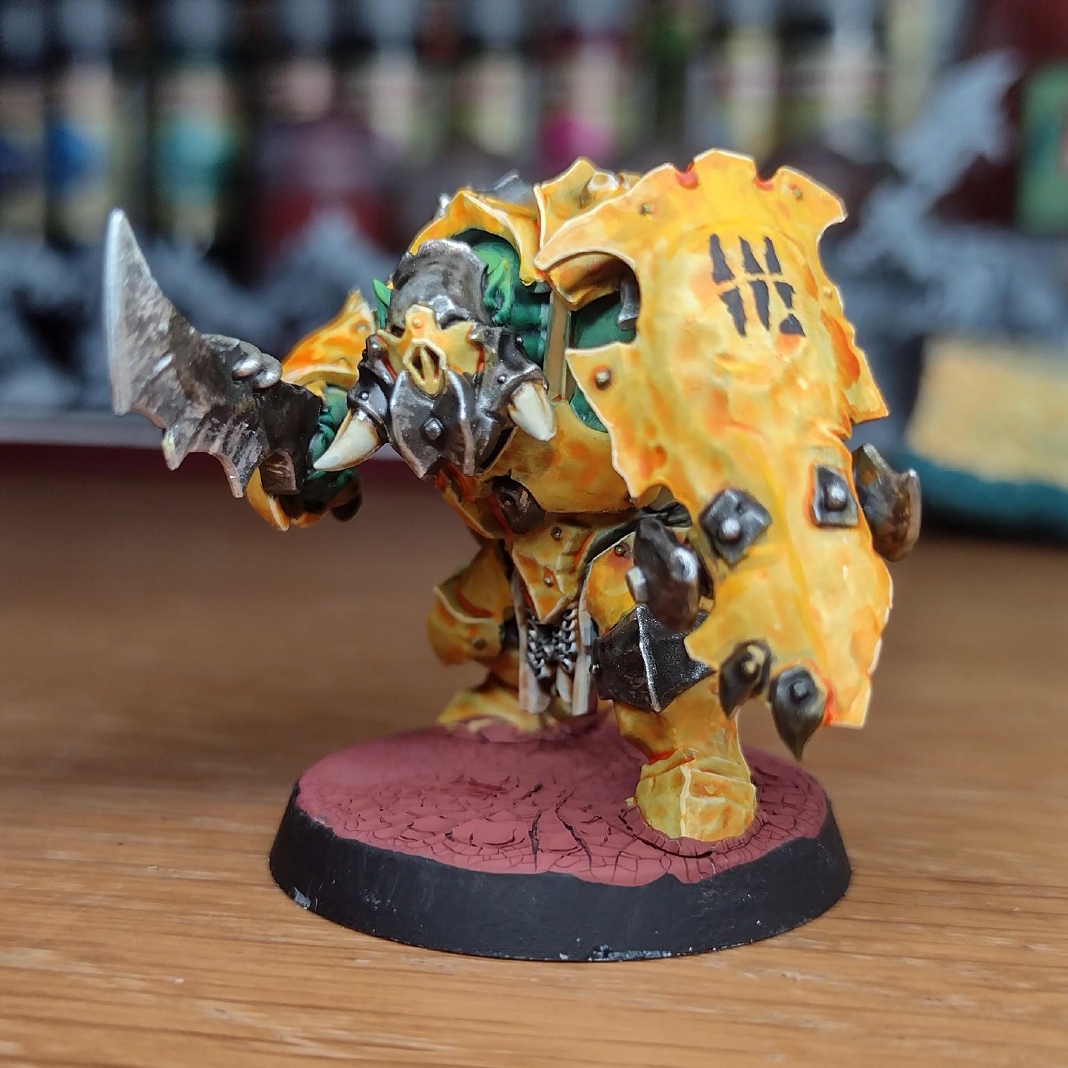 Painted miniature of an orc with a heavy yellow armour, a crude sword, and a huge shield.
