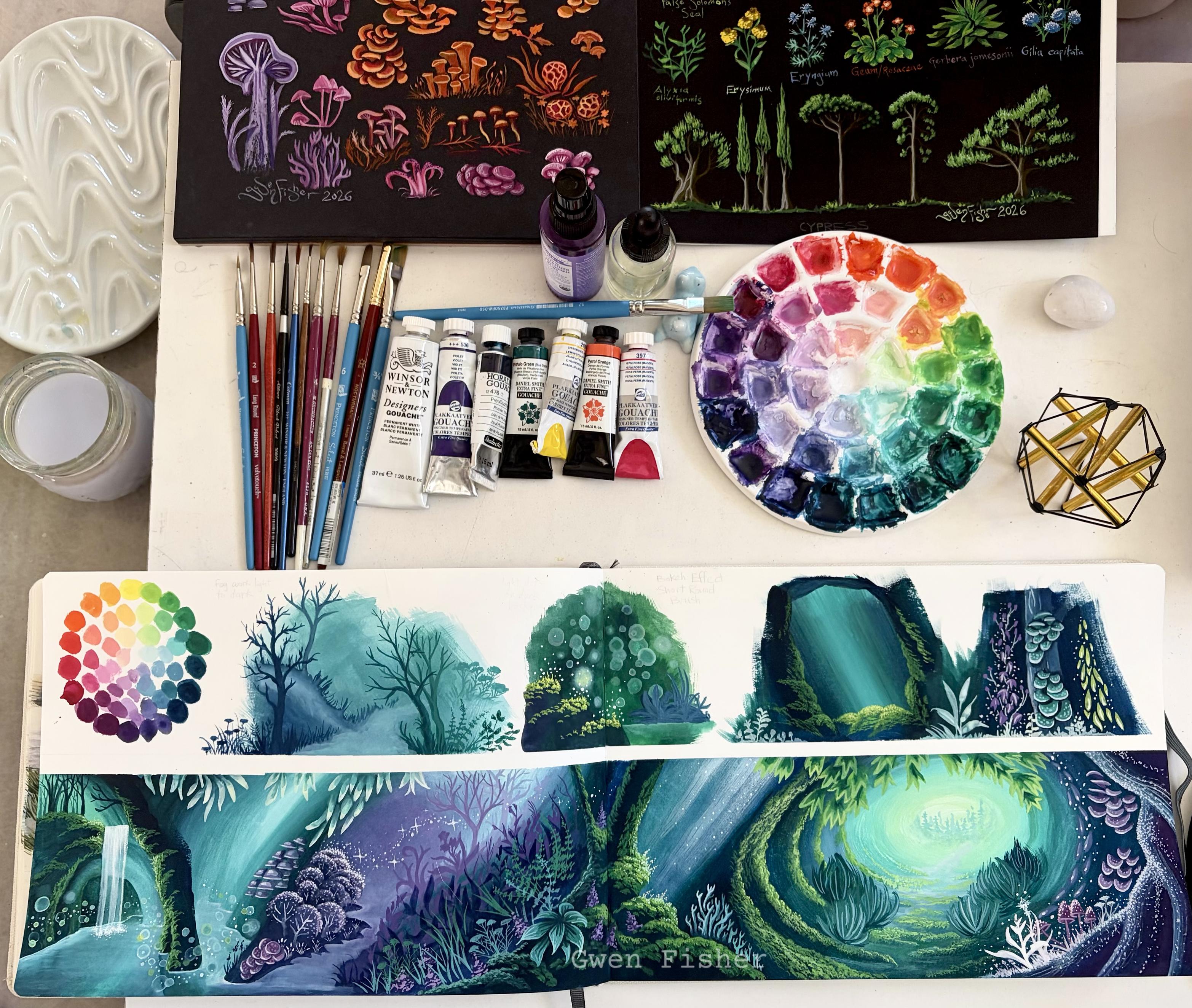 Photo of long painting, art supplies, and reference paintings on black paper of plants and mushrooms. The long paintings consists of a top row of a color wheel and four landscape studies. The bottom row is a long, wide fantasy landscape.  The colors are cool, vibrant, and cheerful. The style is cartoonish and magical.