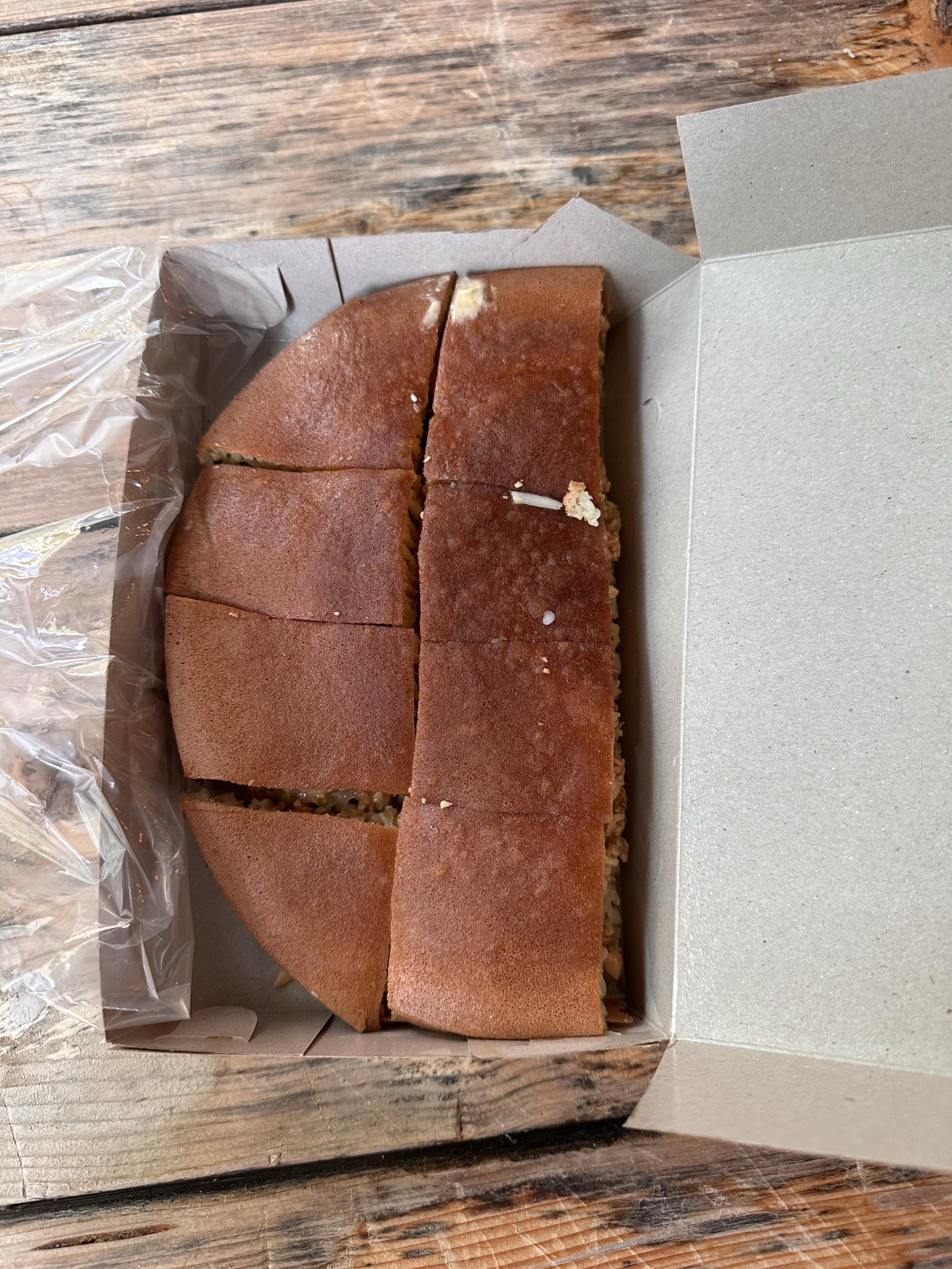 The martabak manis inside the box. It’s half moon shaped, brown beyond golden, and cut into 8 pieces.